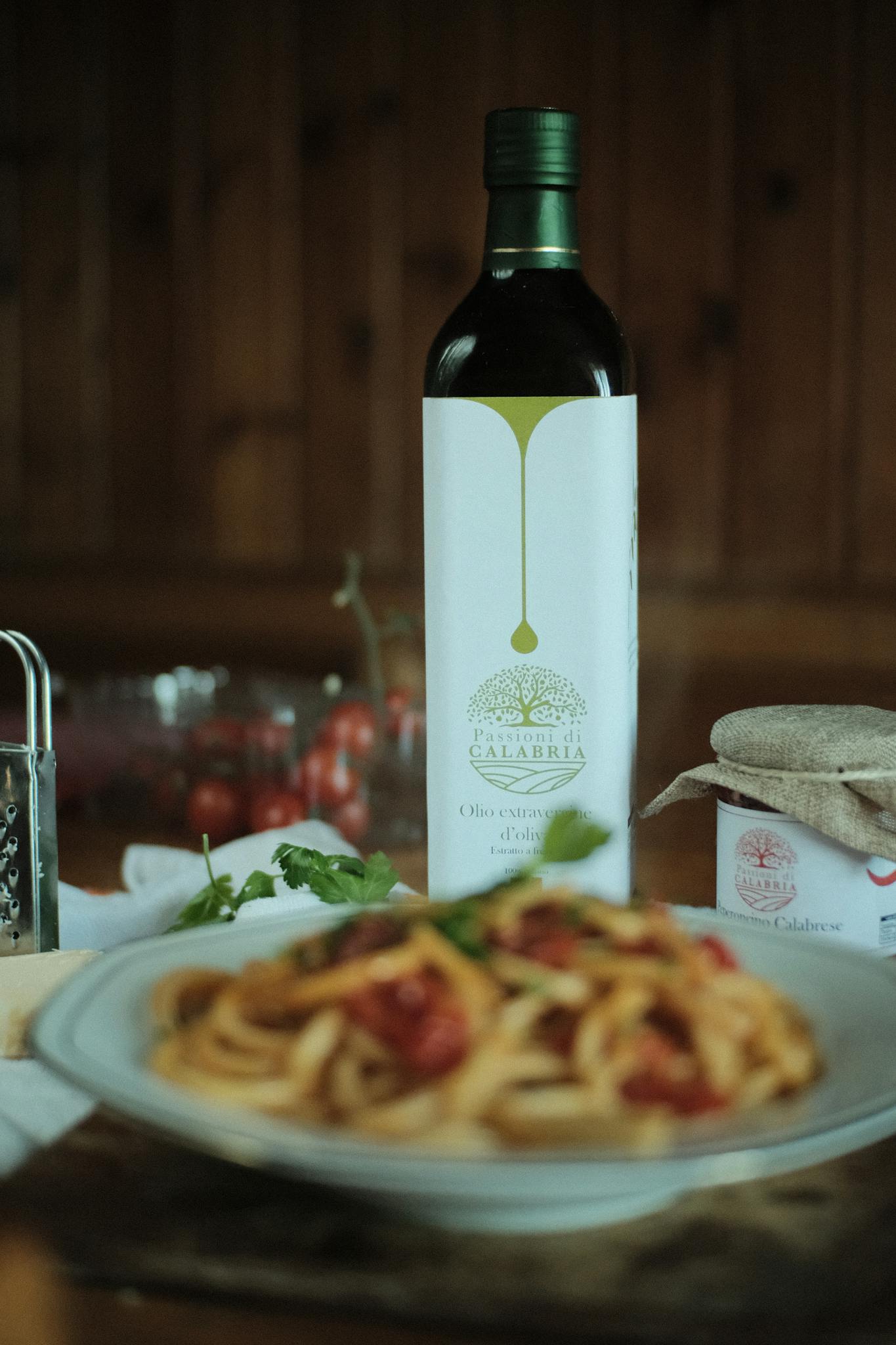 Close-up of Italian pasta and Calabria olive oil, showcasing a gourmet dinner setting.